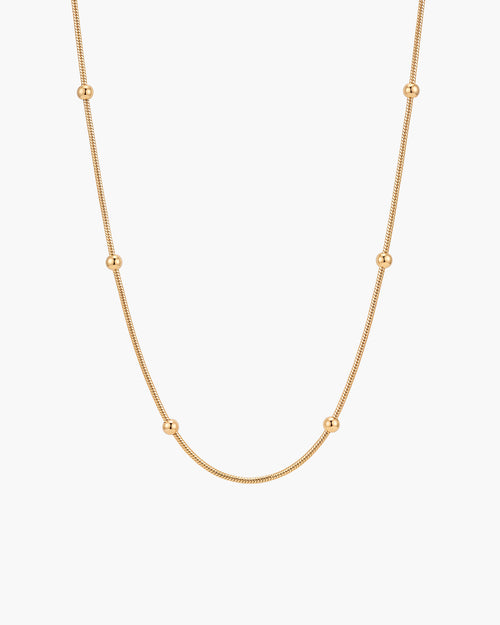 Collar Bella, cadena snake fina en tono dorado con cuentas doradas pulidas a intervalos regulares, sobre fondo blanco